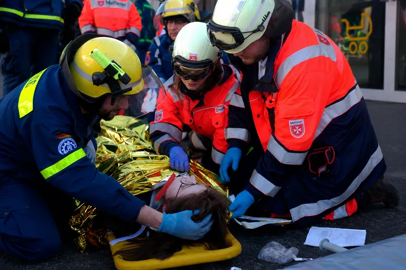 Einsatzkräfte von THW und Malteser Hilfsdienst versorgen eine verletzte Person auf einer Trage unter einer Rettungsdecke