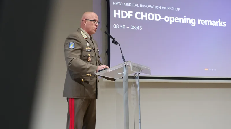 Ungarischer Offizier in Uniform hält bei einer NATO-Konferenz zur Wehrmedizin eine Rede an einem transparenten Rednerpult