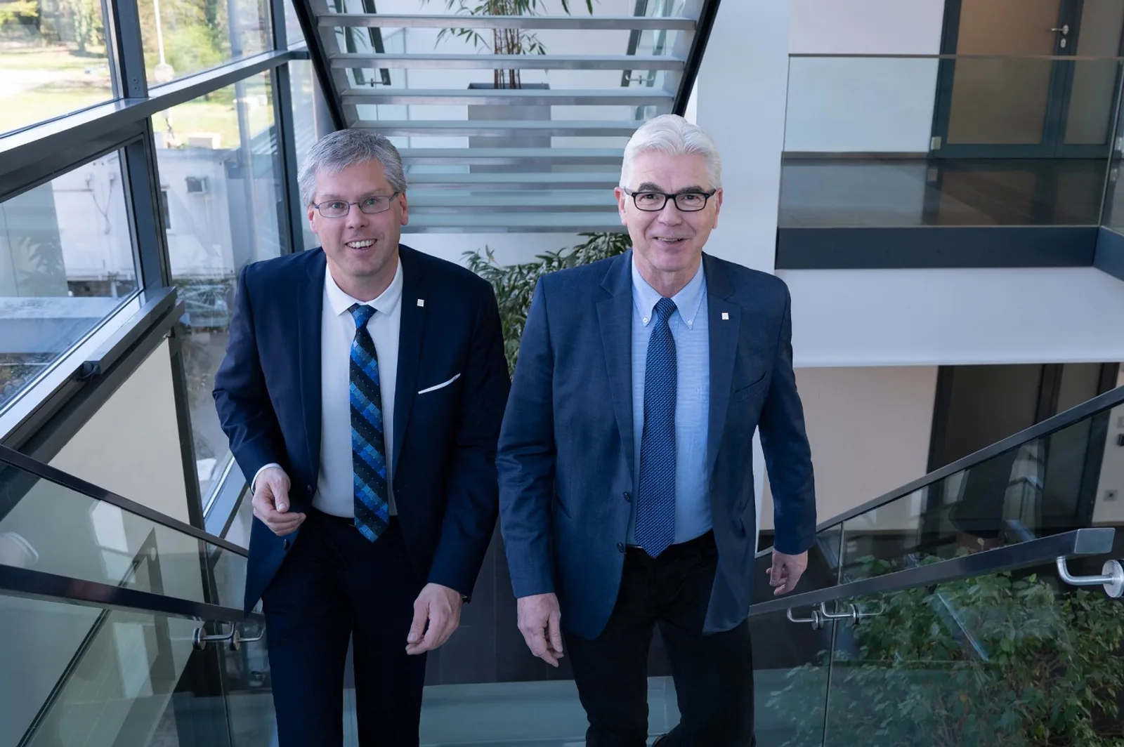 Die Wissenschaftler Eichhorn und Prof. Dr. Jürgen Beyerer im Gespräch auf einer Treppe in einem modernen Bürogebäude des Fraunhofer-Instituts.