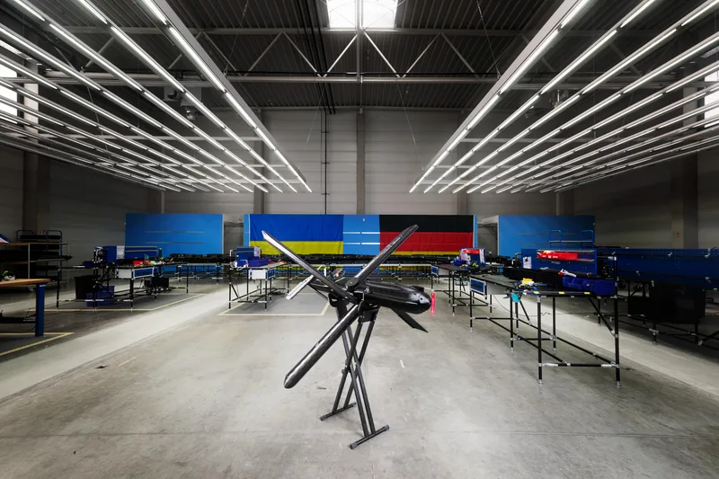 Drohne vom Typ Seth X auf einem Montagebock in einer Produktionshalle mit ukrainischen und deutschen Flaggen im Hintergrund