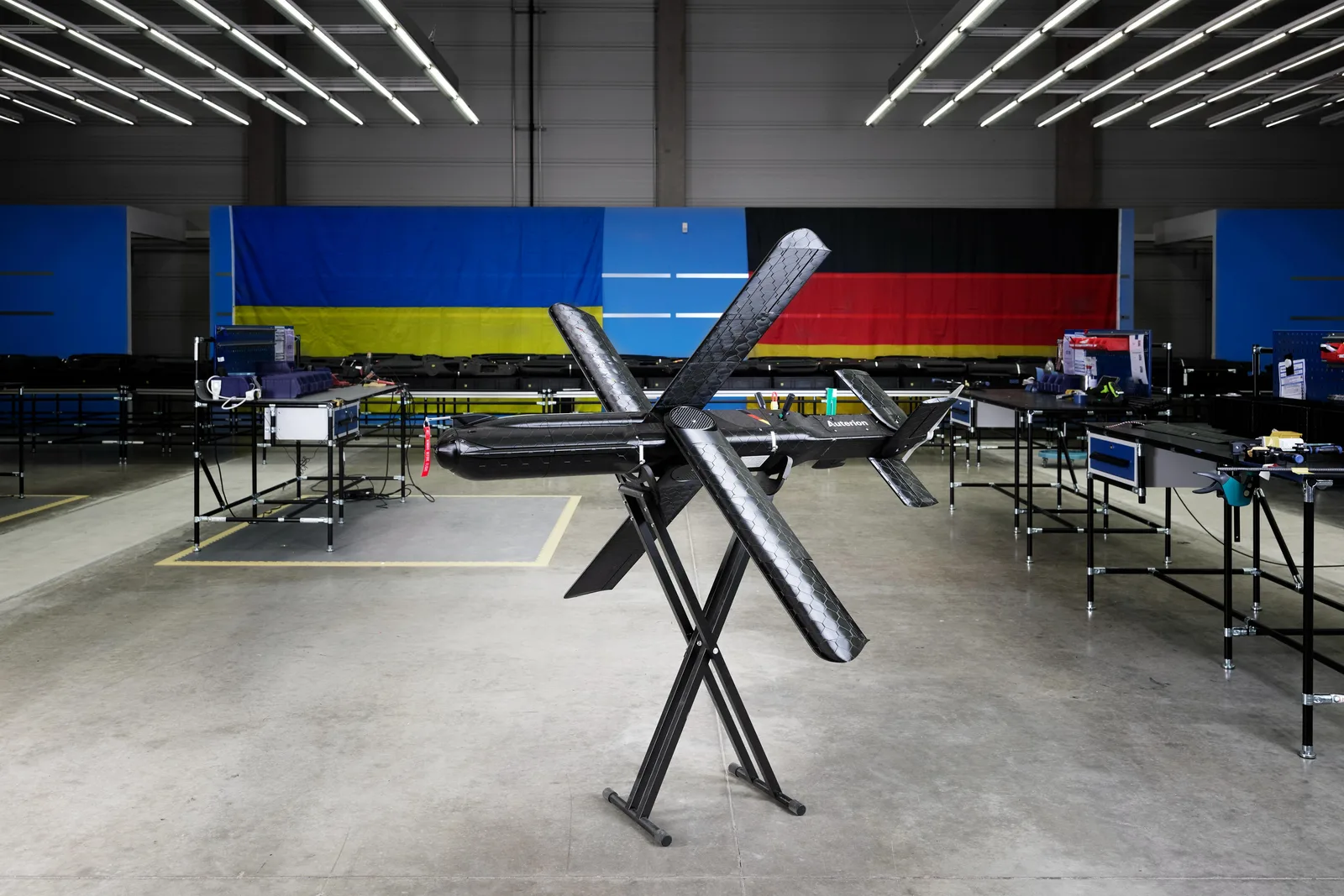 Drohne vom Typ Seth X von Auterion auf einem Montagegestell in einer Produktionshalle mit ukrainischer und deutscher Flagge