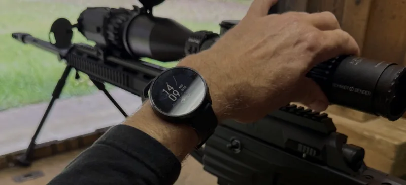 Schütze justiert ein Schmidt & Bender Zielfernrohr auf einem Präzisionsgewehr, am Handgelenk ist eine Smartwatch sichtbar