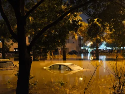 MESHFREE: Überschwemmtes Wohngebiet bei Nacht mit im Wasser versunkenen Fahrzeugen und einer fast untergegangenen weißen Limousine