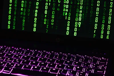 Berlin: Geöffnetes HP-Notebook mit violett beleuchteter Tastatur und grünem Programmcode auf dem Bildschirm.