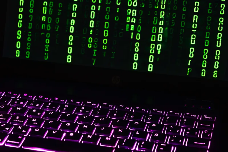 Berlin: Geöffnetes HP-Notebook mit violett beleuchteter Tastatur und grünem Programmcode auf dem Bildschirm.