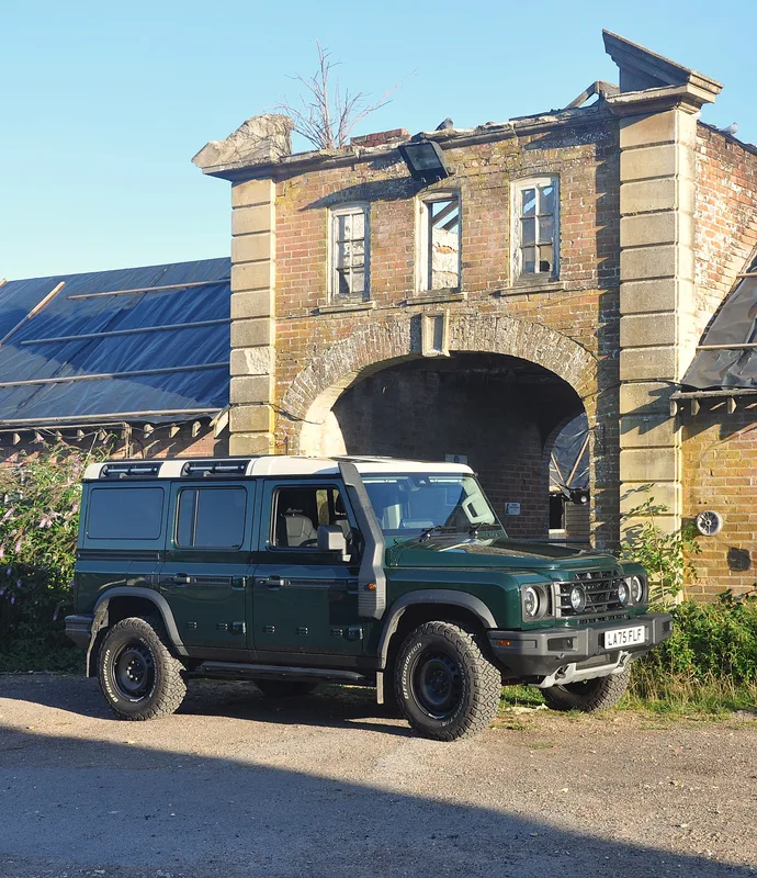Ineos Grenadier Geländewagen mit Offroad-Ausrüstung vor einem beschädigten historischen Backstein-Torbogen im Crabbet Park