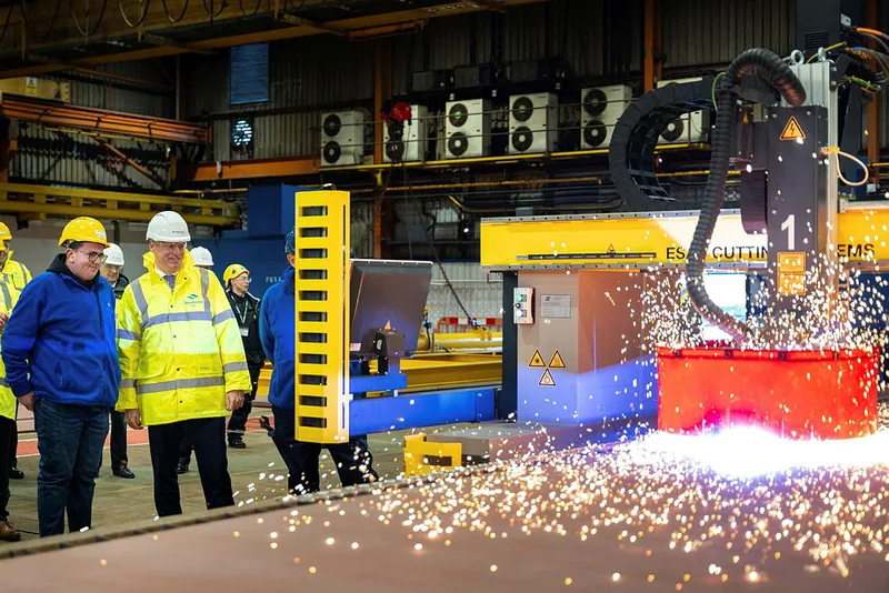 Luke Pollard in gelber Warnjacke beobachtet in der Appledore-Werft den automatisierten Stahlzuschnitt durch eine ESAB-Schneidanlage
