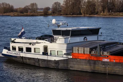 Rhein: Gütermotorschiff Michaelangelo transportiert Fracht auf einer Wasserstraße mit einem schwarzen Pkw auf dem Achterdeck