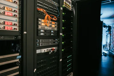 CRA: Systemschränke in einem Technikraum mit Sennheiser-Audioempfängern, Netzwerkkomponenten und strukturierter Verkabelung