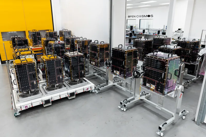Mehrere Kleinsatelliten auf Montagevorrichtungen in einer Reinraum-Fertigungshalle von Open Cosmos