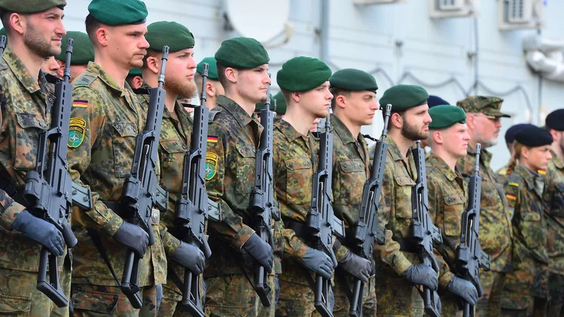 Litauen: Soldaten der Bundeswehr in Flecktarn-Uniformen und grünen Baretts mit G36-Sturmgewehren bei einem militärischen Appell