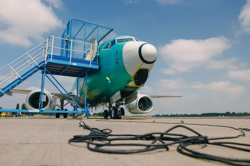 Boeing E-7A Wedgetail im grünen Grundieranstrich mit mobiler blauer Wartungsbühne am Cockpit auf einem Flugplatzvorfeld