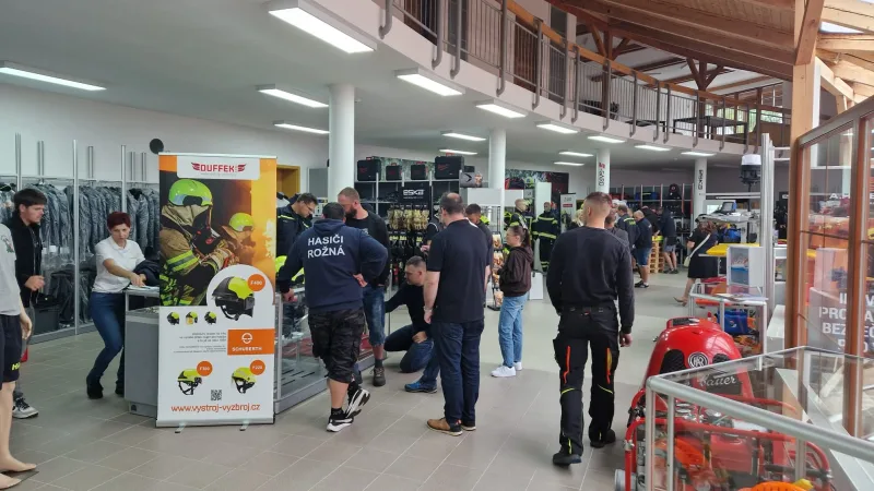 Besucher betrachten auf einer Fachmesse für Sicherheitstechnik Feuerwehrhelme von Schuberth vor einem Werbebanner der Firma Duffek