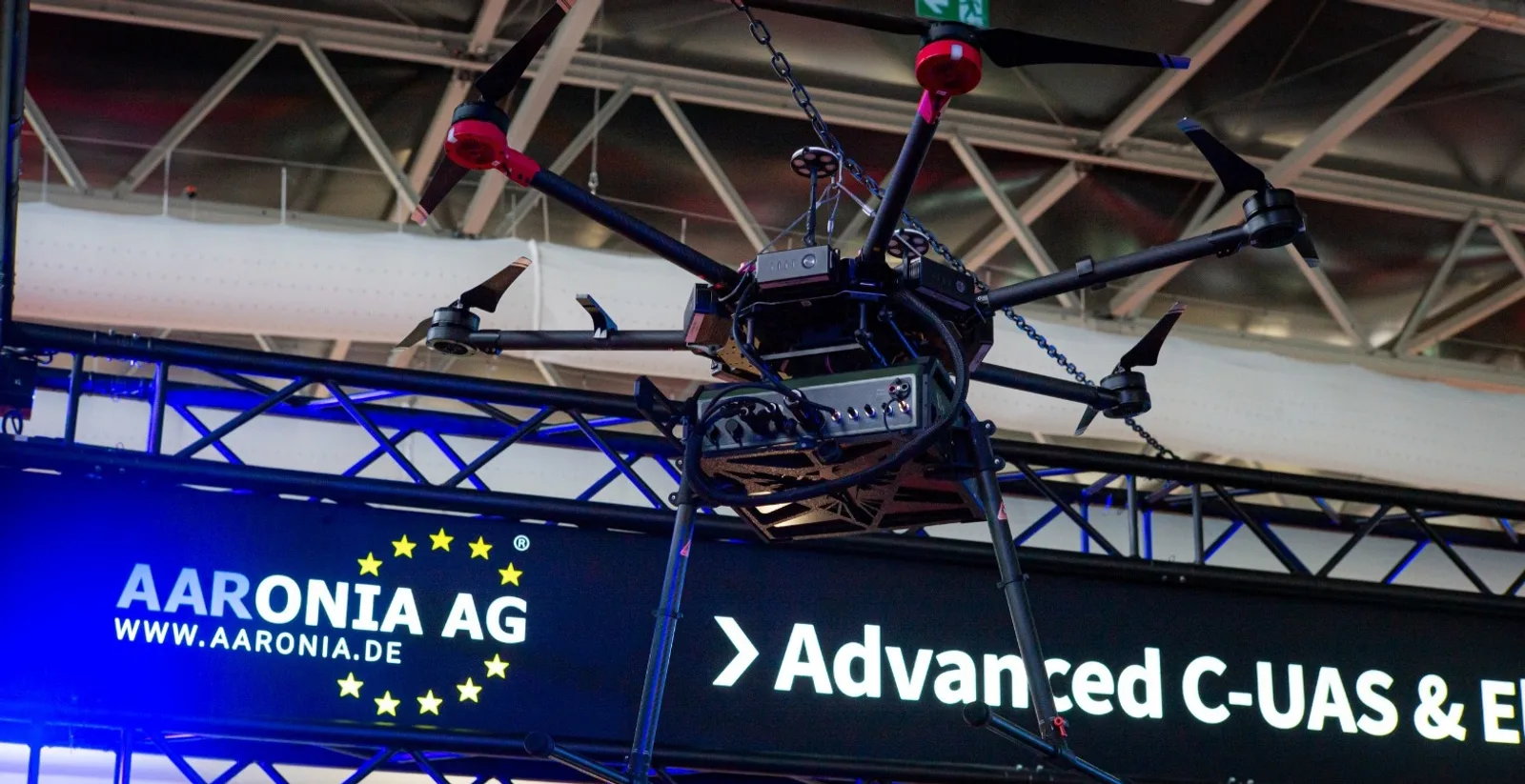 Multikopter-Drohne AARTOS HAWK T1 mit Sensorik über dem Messestand der Aaronia AG auf einer Fachmesse für Sicherheitstechnik