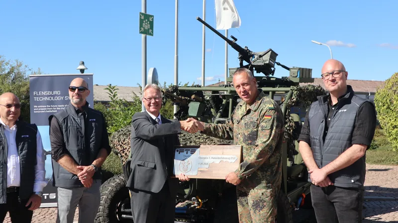 Vertreter von Flensburg Technology Systems überreichen einem Bundeswehr-Offizier eine Plakette vor dem Vorserienfahrzeug TAHR
