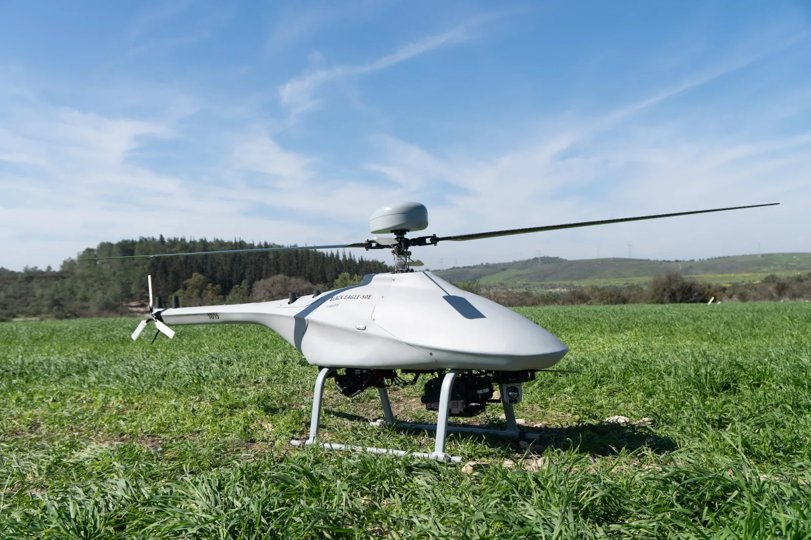 Unbemannte Aufklärungsdrohne Black Eagle 50E von Steadicopter mit optischer Sensoreinheit auf einer Wiese stehend