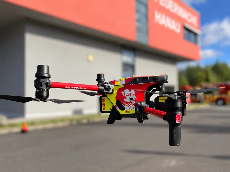 Drohne DJI Matrice 30 der Feuerwehr Hanau im rot-gelben Design mit Stadtwappen im Schwebeflug vor der Feuerwache