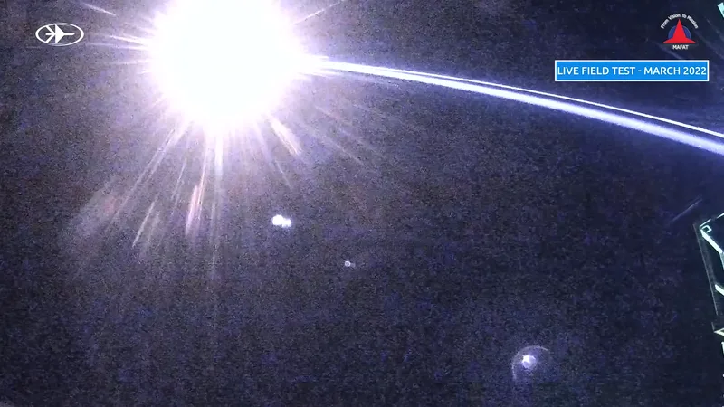 An Iron Beam engagement of a mortar bomb during a March 2022 test. The beam here is made visible due to the use of a near-infrared or short-wave infrared camera. Lasers used by HELs are typically in the infrared portion of the spectrum, and so are invisible to the naked eye.