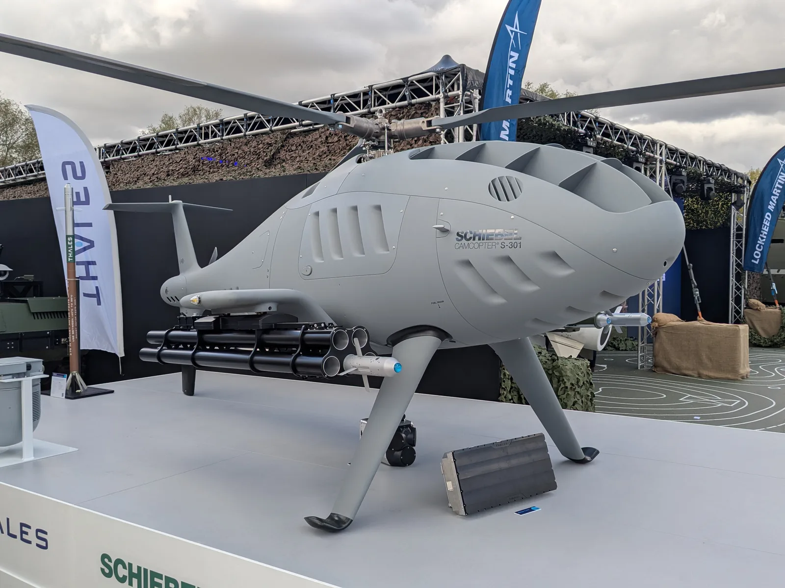 A Schiebel Camcopter S-301 rotary-wing UAV was displayed on the Thales UK stand at DVD 2026 configured with two pods armed with Thales FZ275 guided rockets.