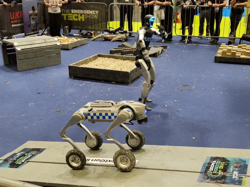 Vierrädriger Roboter NextGen R1 und ein humanoider Roboter auf einem Hindernisparcours während einer Fachmesse für Rettungstechnik