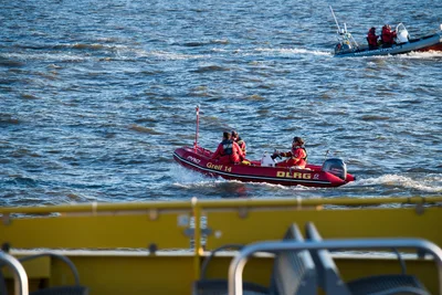 DLRG-Rettungsboot von Zodiac mit Yamaha-Außenbordmotor und drei Einsatzkräften auf dem Wasser vor einem Boot der Wasserschutzpolizei