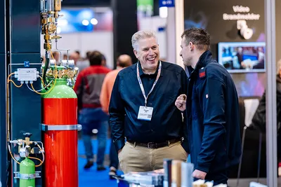 Zwei Fachbesucher im Gespräch an einem Fire Eater Messestand mit Gas-Löschanlage auf den VdS-Brandschutztagen