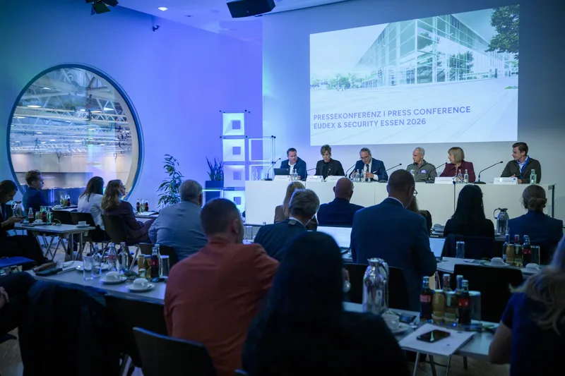 Referenten auf einem Podium vor einer Präsentationsleinwand bei der Pressekonferenz zu den Fachmessen EUDEX und Security Essen 2026