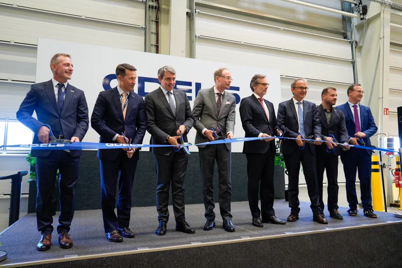 Vertreter aus Politik und Wirtschaft schneiden bei einer Einweihung vor dem Logo von General Dynamics European Land Systems ein Band
