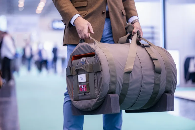 Mitarbeiter präsentiert zylindrischen Garant-Schutzbehälter für unkonventionelle Sprengvorrichtungen auf einer Fachmesse