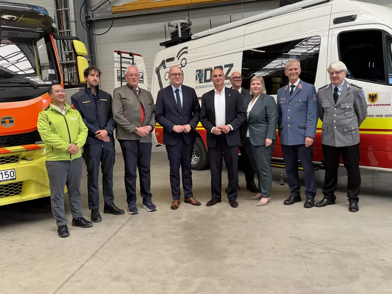 Rettungsrobotik: Vertreter von Bundeswehr, Feuerwehr Dortmund und DRZ vor Einsatzfahrzeugen und einem mit Sensortechnik ausgestatteten Trägerfahrzeug