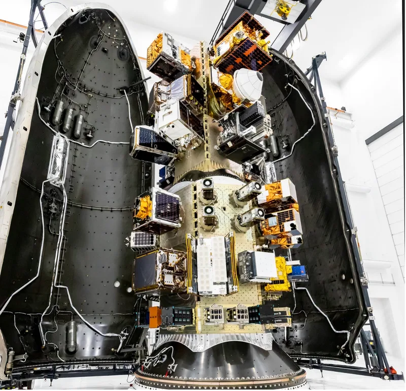 Mehrere Kleinsatelliten auf einem Nutzlastadapter innerhalb der geöffneten Verkleidung einer SpaceX Falcon-9-Trägerrakete