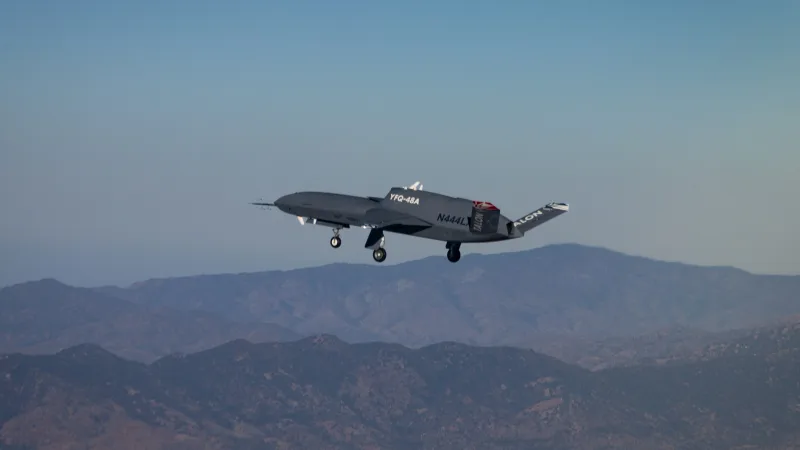 Northrop Grumman treibt die Entwicklung autonomer Luftstreitkräfte mit dem ersten Flug des „Talon Blue“ voran Unbemanntes Flugsystem YFQ-48A mit ausgefahrenem Fahrwerk im Flug über einer bergigen Landschaft