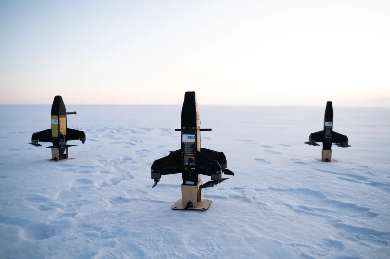 Drei unbemannte Flugsysteme mit Rotoren an den Tragflächen stehen startbereit in einer schneebedeckten Landschaft