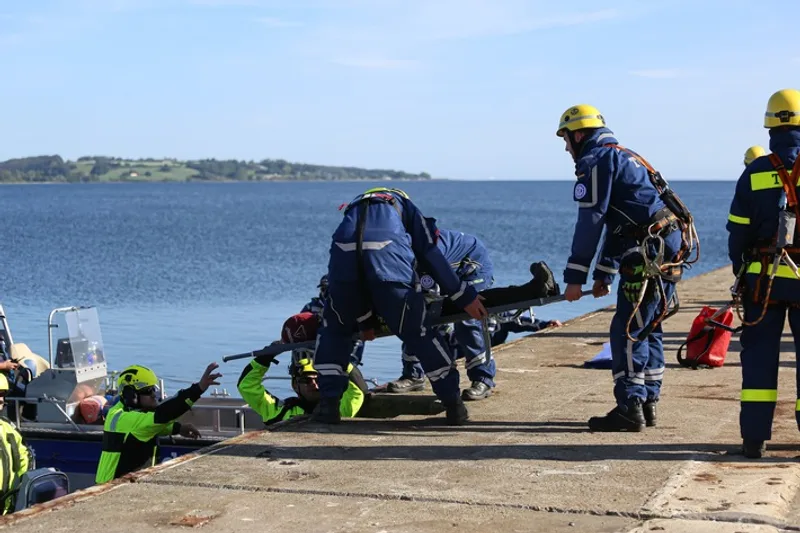 Einsatzkräfte des THW bergen bei einer Rettungsübung eine Person auf einer Trage von einem Boot auf eine Kaimauer