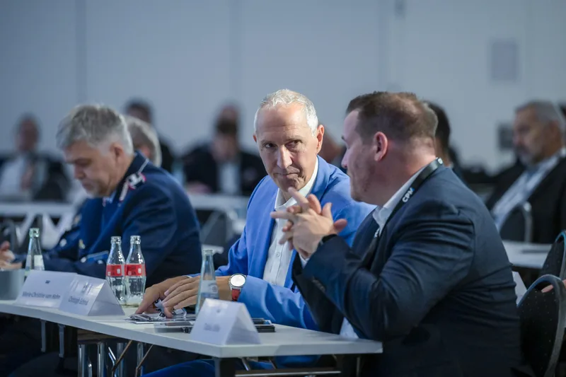 Teilnehmer einer Fachkonferenz mit einem Bundeswehroffizier der Luftwaffe im Dienstanzug sitzen an einem Konferenztisch
