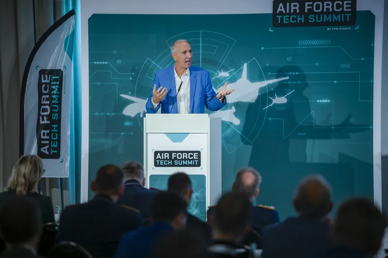 Referent am Rednerpult während des Air Force Tech Summit vor Fachpublikum auf einer Bühne mit Luftfahrt-Grafiken