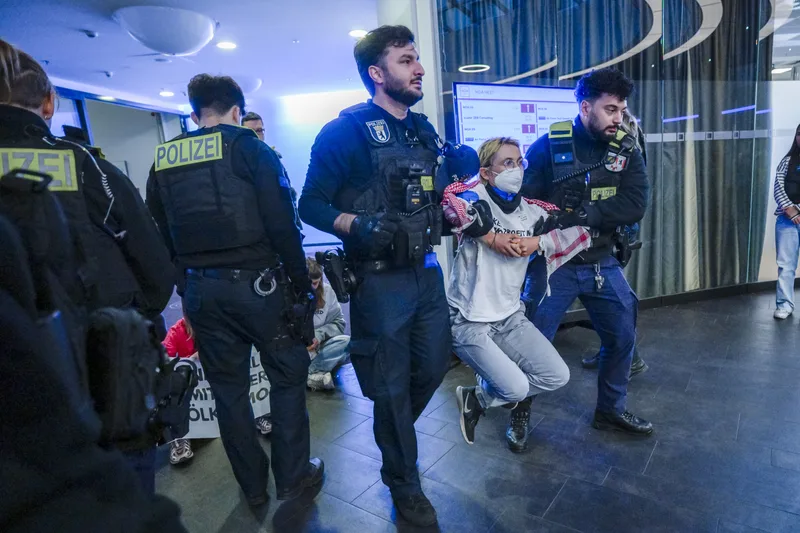 Berliner Polizei führt bei einem Air Force Tech Summit eine protestierende Person aus einem Tagungsraum ab