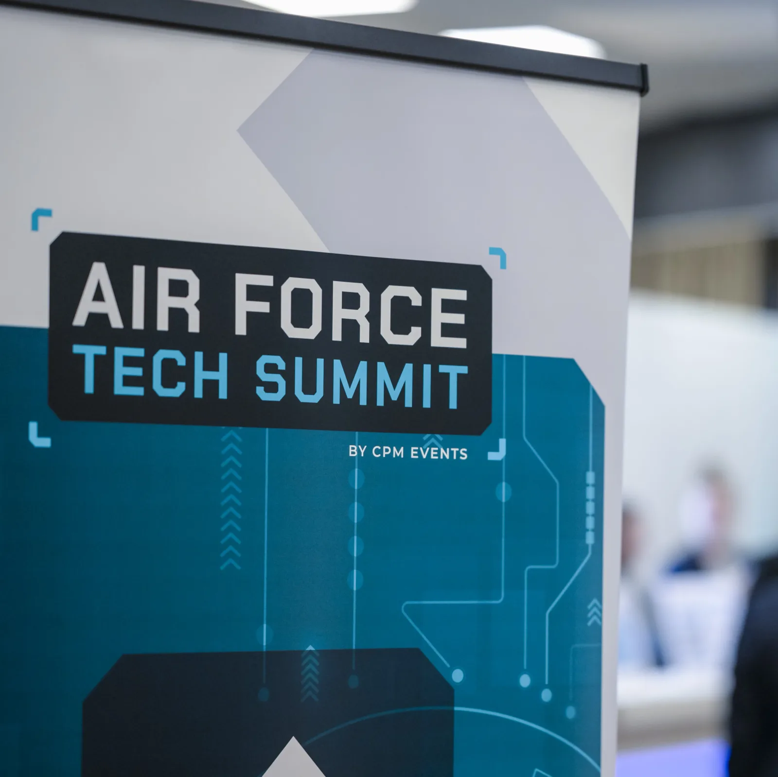 Informationsaufsteller zur Fachkonferenz Air Force Tech Summit von cpm events im Eingangsbereich mit unscharfen Konferenzteilnehmern