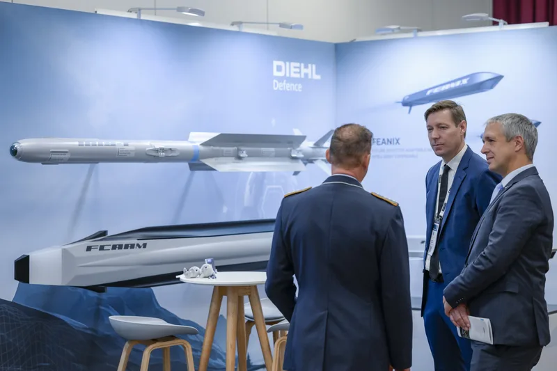 Luftwaffenoffizier im Gespräch mit Vertretern von Diehl Defence vor Modellen der Lenkflugkörpersysteme FCAAM und FEANIX