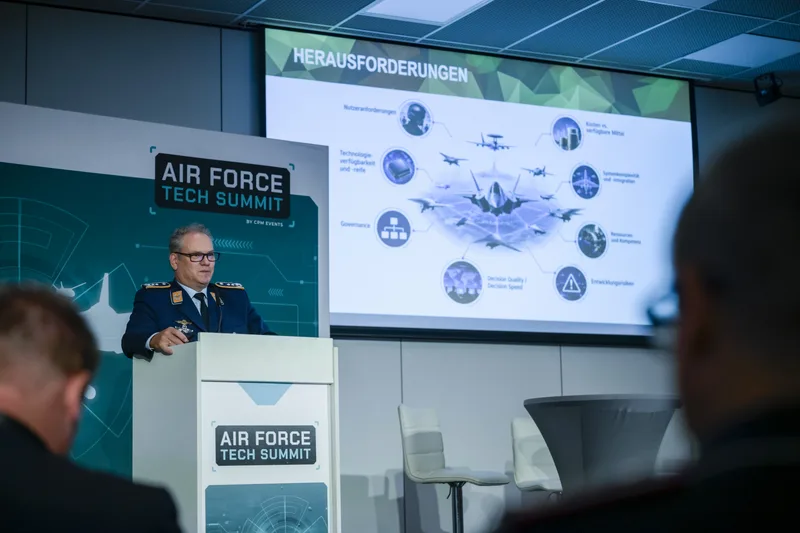 Oberst der Luftwaffe hält bei einem Air Force Tech Summit einen Vortrag vor einer Projektionswand mit Schaubildern zur Luftfahrttechnik