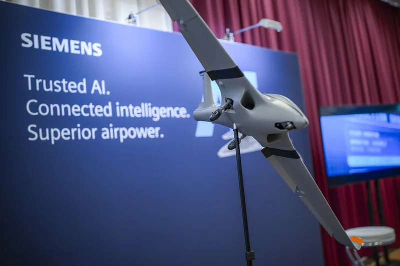 Modell einer Drohne auf einem Präsentationsständer vor einer Siemens-Ausstellungswand zu künstlicher Intelligenz und Luftstreitkräften