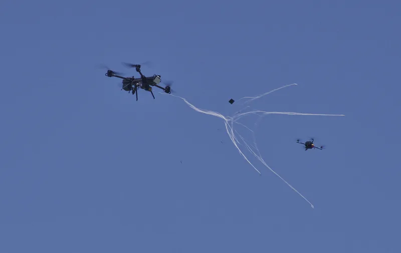 Abfang-Multikopter des Projekts FALKE schießt im Flug ein Fangnetz auf eine Zieldrohne zur Drohnenabwehr