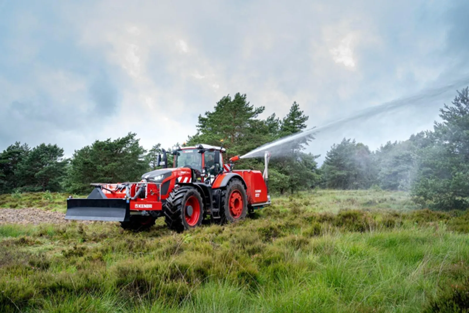 Kenbri-Löschtraktor mit Fronträumschild gibt bei einer Geländeerprobung Wasser über einen Löschwerfer ab