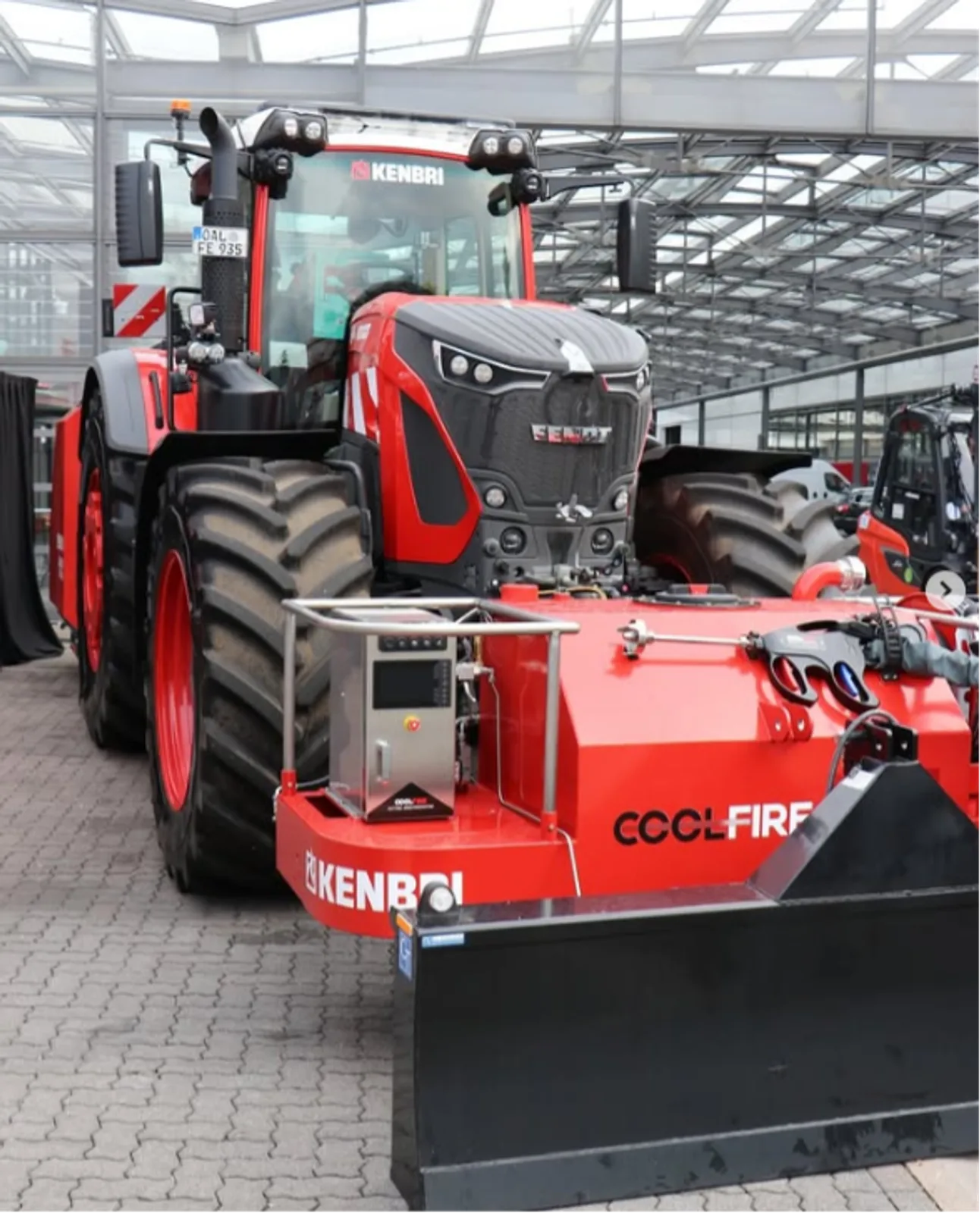 Roter Fendt-Traktor mit Kenbri-Frontanbau, Coolfire-Löschsystem und Räumschild auf einem befestigten Freigelände vor einer Halle