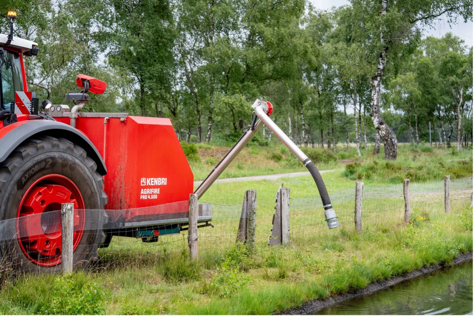 Traktor der Marke Fendt mit Kenbri Agrifire Pro 4.500 Löschaufbau entnimmt mit ausfahrbarem Saugrohr Wasser aus einem Gewässer