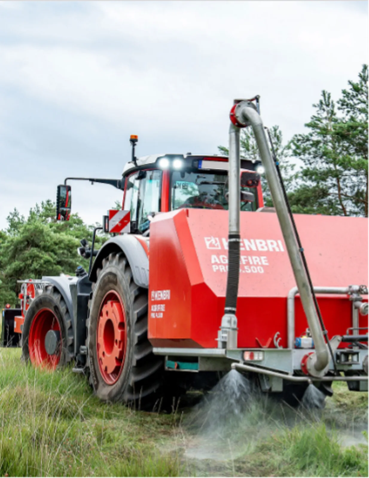 Fendt-Traktor mit Kenbri Agrifire-Löschsystem bei der Wasserabgabe über Heckdüsen in bewachsenem Gelände
