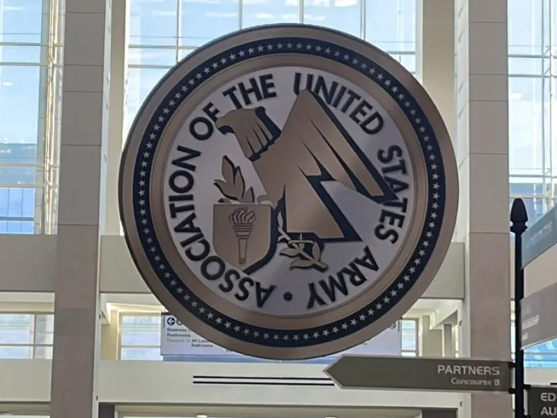 Emblem der Association of the United States Army (AUSA) im Foyer eines Kongresszentrums mit Tagungsbesuchern und Soldaten in Dienstanzügen