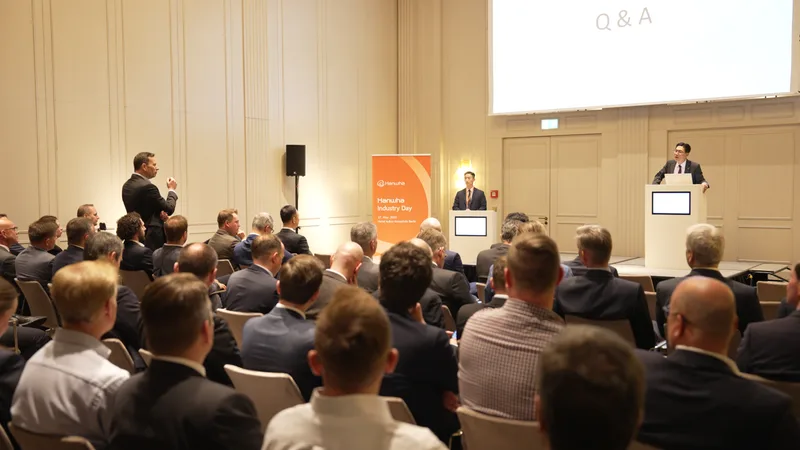 Referenten am Rednerpult und ein Fragesteller im Publikum während des Hanwha Industry Day im Hotel Adlon Kempinski in Berlin