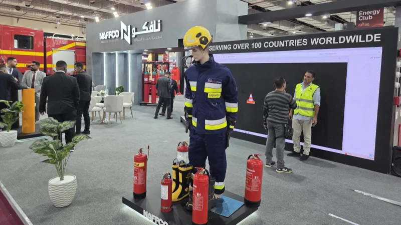 Messestand von NAFFCO mit Feuerwehrschutzkleidung an einer Schaufensterpuppe, Feuerlöschern, Messebesuchern und einem Feuerwehrfahrzeug