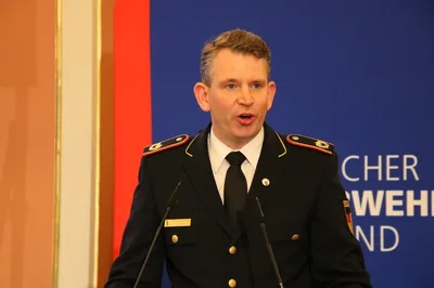 Dr. Christoph Weltecke in Feuerwehruniform spricht an einem Rednerpult vor dem Logo des Deutschen Feuerwehrverbandes